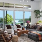 Modern living room with large windows, sofa, and ceiling fan.