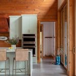 Wooden kitchen with pale green cabinets, a leather island, and a stainless steel range.