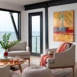 Gray upholstered chairs, coffee table, and artwork in a coastal interior.