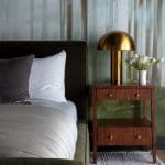 Dark forest wallpaper with a gold table lamp and nightstand.