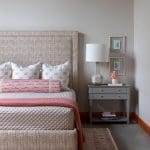 Gray bed with patterned headboard, lamp, and nightstand.