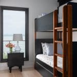 Bunk bed with navy headboard, wooden ladder, and blue-and-white sailboat bedding.