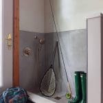 Small bathroom with shower, fishing gear, and boots.