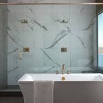 White marble shower with brass fixtures and a freestanding tub.