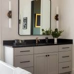 Gray vanity with black marble countertop and mirror.