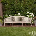 Wooden bench in front of a white hydrangea hedge.