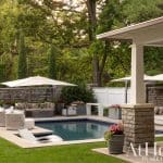 Outdoor patio with pool, umbrellas, and stone seating.