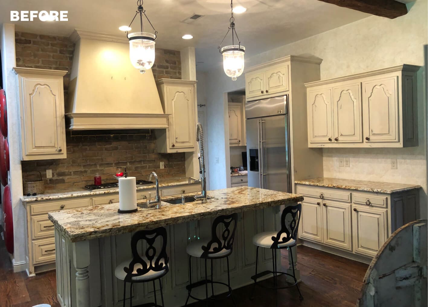 Gray kitchen cabinets, stone island, and pendant lighting.