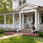 White Victorian house with a wide porch and landscaping.