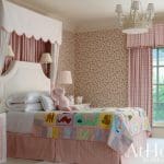 Pink floral wallpaper bedroom with a canopy bed and quilt.