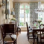 Formal dining room with patterned drapes, chandeliers, and dark wood furniture.