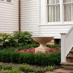 White clapboard house with a stone planter and landscaping.