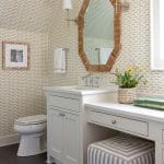 Powder room with patterned wallpaper, mirror, and vanity.