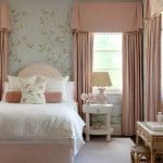 Pink bedroom with floral wallpaper, pink curtains, and bedding.