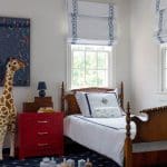 Blue and white window treatments, red dresser, and wooden bed frame.