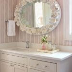 Pink and white striped wall with a large, ornate mirror and vanity.