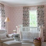 Pink floral wallpaper, curtains, and a nursery setting.