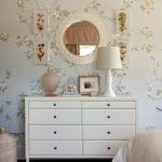 Light blue wall with floral wallpaper, mirror, and dresser.