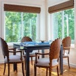 White room with large windows, bamboo shades, and a dark wood dining table.