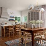 Kitchen with light gray cabinets, wood island, white tile backsplash, and dining table.
