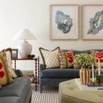 Blue sofa with patterned pillows, abstract art, and a white lamp on a side table.