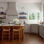Kitchen with light gray cabinets, wood island, tile backsplash, and wooden floor. Features blue