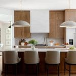 Kitchen with wood cabinetry, marble island, and pendant lights.