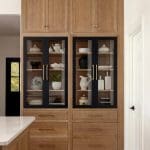 Wooden cabinetry with glass doors displaying white pottery and dishes.