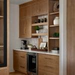 Built-in wood cabinetry with white tile backsplash, coffee maker, mini fridge, and glassware.