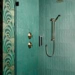 Teal subway tile shower with brass fixtures and geometric wallpaper