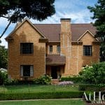 Two-story brick house with dark windows and a prominent brick chimney.