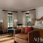 Bedroom with rattan headboard, patterned bedding, and a desk with a chair.