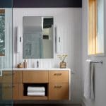 Modern bathroom with wood vanity, white tile, and glass shower