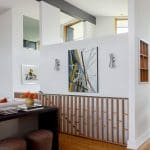 Modern living area with abstract art, wooden slatted railing, and contemporary furniture.