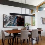 Dining room with wood table, gray chairs, abstract art, and modern chandelier.