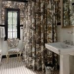 Bathroom with toile wallpaper, patterned shower curtain, pedestal sink, and mosaic tile floor.