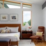 Bedroom with wood-framed windows, leather headboard, and mid-century modern furniture.