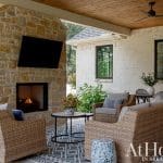 Covered patio with stone fireplace, wicker furniture, and wood ceiling
