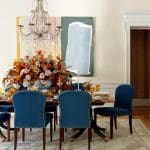 Dining room with blue velvet chairs, large floral arrangement, and crystal chandelier