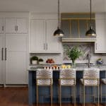 Blue kitchen island with tiger-print bar stools, gray cabinetry, and pendant lights.