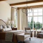 Bedroom with upholstered headboard, patterned pillows, and wood beams.
