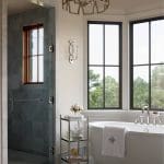 Luxury bathroom with freestanding tub, marble shower, and ornate chandelier.