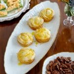 Puff pastry bites with orange zest on a white platter.