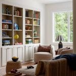 Living room with built-in white bookshelves, plush armchairs, and striped sofa.