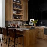 Wood bar with marble countertop, leather stools, and black tile backsplash