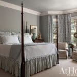 Bedroom with four-poster bed, white bedding, grey walls, and floral curtains.