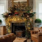 Living room fireplace with brick surround, festive garland, and leather armchair.