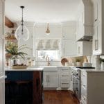 White kitchen with navy island, subway tile backsplash, and brass hardware