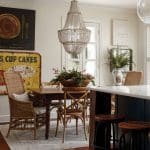 Dining room with wicker chairs, wooden table, beaded chandelier, and vintage signs.