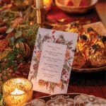 Table setting with a Winter Solstice menu, candle, and festive decorations.
